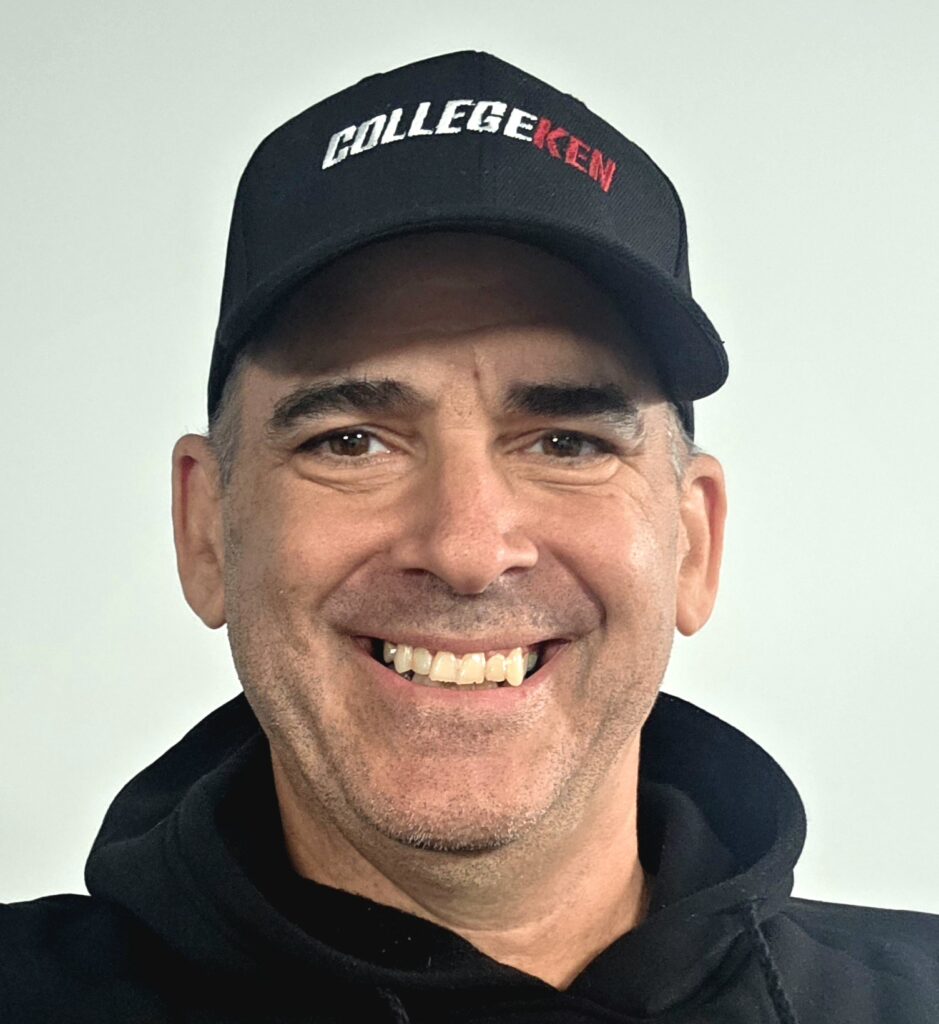 CollegeKen smiling, in a black hoodie and black baseball with CollegeKen embroidered on it